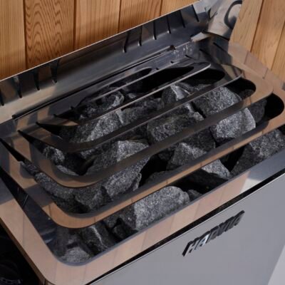 Harvia wall-mounted sauna heater with stone basket and wooden safety guard inside cedar sauna.