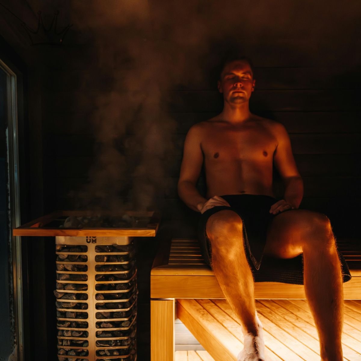 A man enjoying a relaxing session in a premium home sauna with steam rising from a modern heater, showcasing the deep relaxation benefits of a luxury home resort."