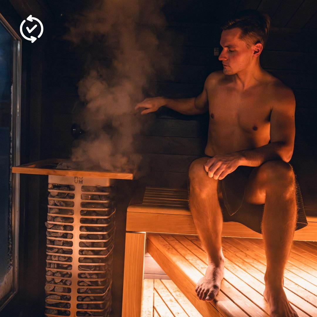 A man enjoying a relaxing session in a premium home sauna with steam rising from a modern heater, showcasing the deep relaxation benefits of a luxury home resort."